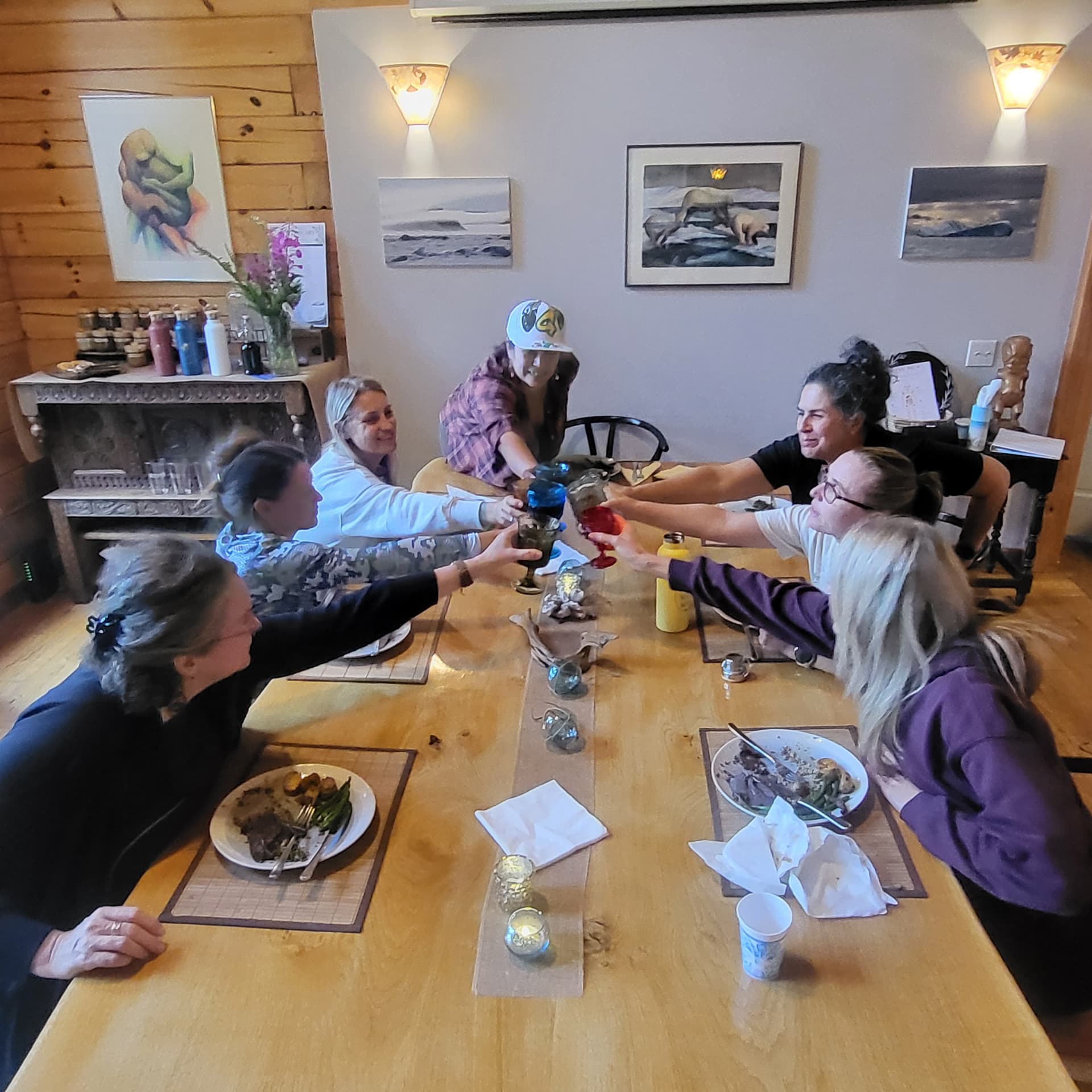 Wild N Well guests raising their glasses around a shared table in Sitka