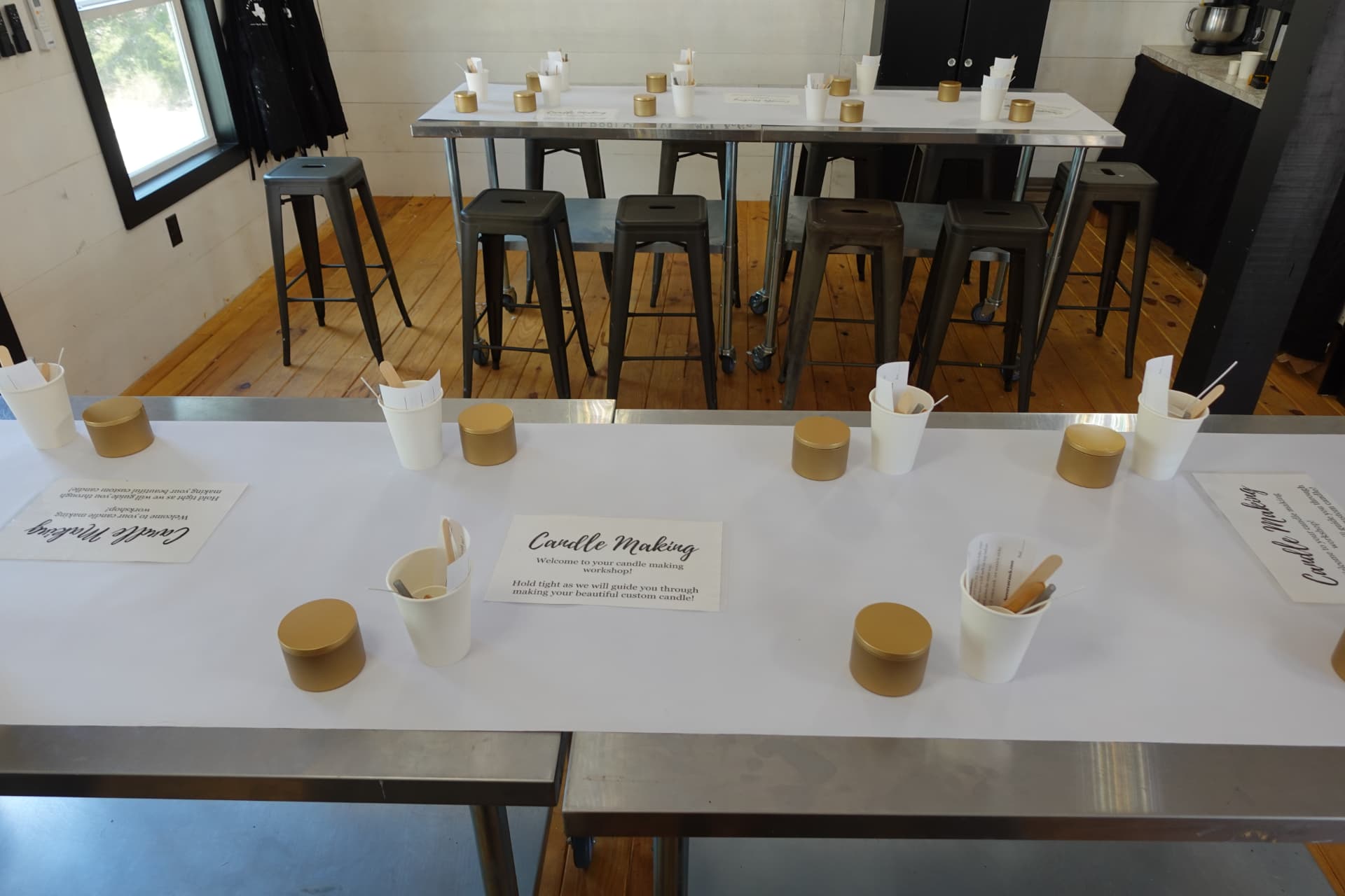 Candle-making tables prepared with gold tins, tools and printed instructions