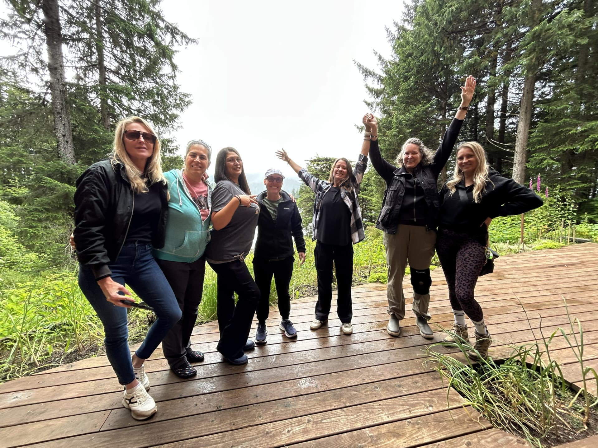 Wild N Well guests celebrating together on a forest deck in Sitka