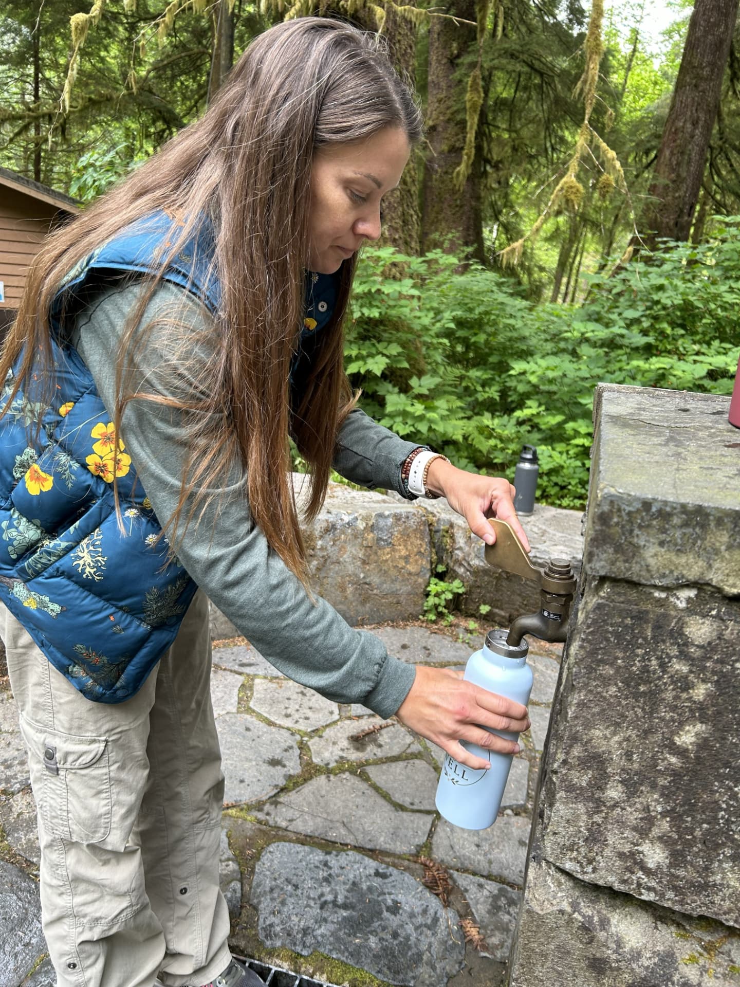 A retreat guest filling her bottle from an artesian well in the forest